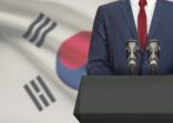 Businessman or politician making speech from behind a pulpit with national flag on background – South Korea