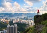 photographer standing on the top of Cliff above Hong kong cityscape