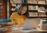 Young lady using a laptop to do research on the internet. Woman working on a project. Mixed race woman sending emails.